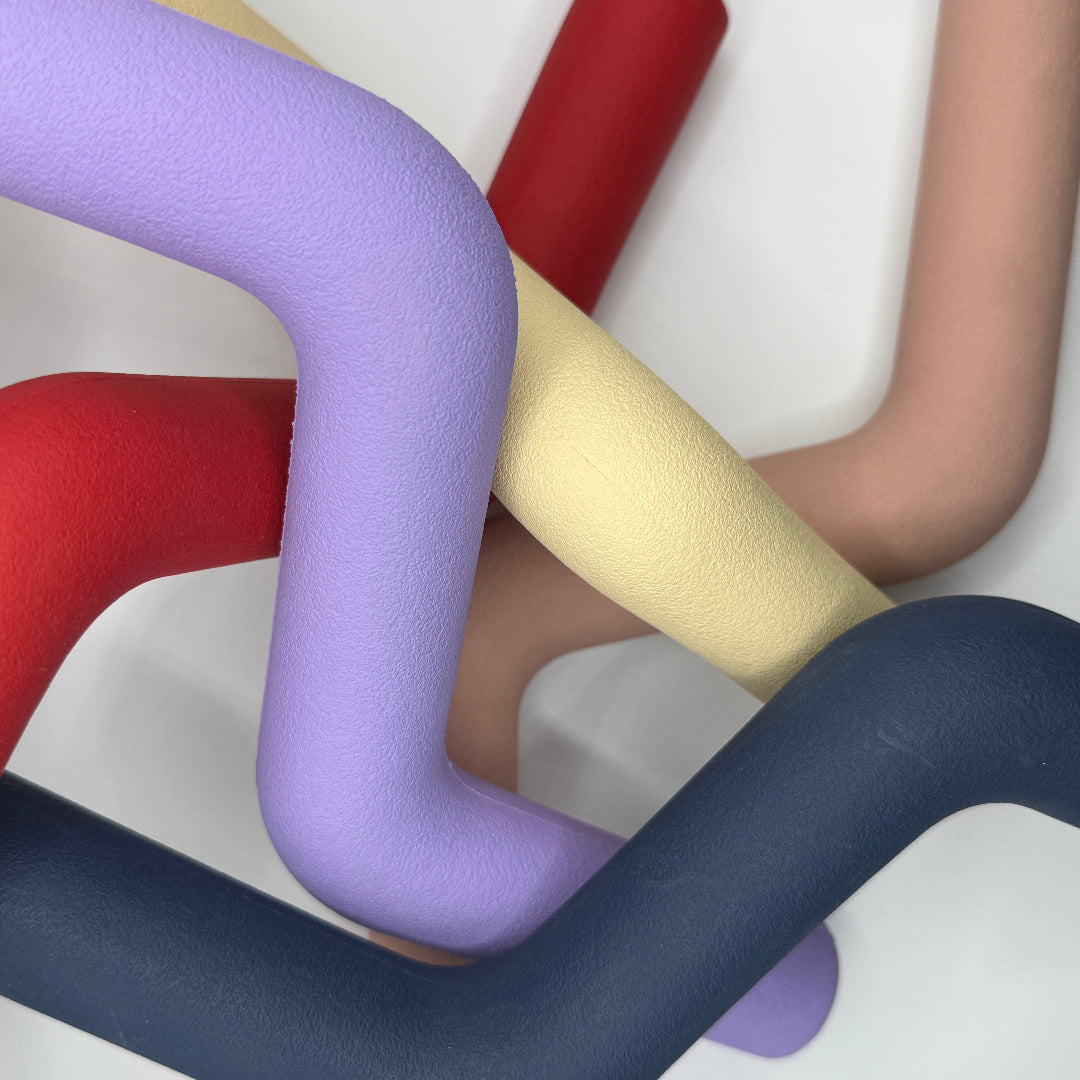 Hond speelt met roze, blauwe, rode, paarse, beige Speeltak van natuurlijk rubber – veilig alternatief voor de klassieke stok